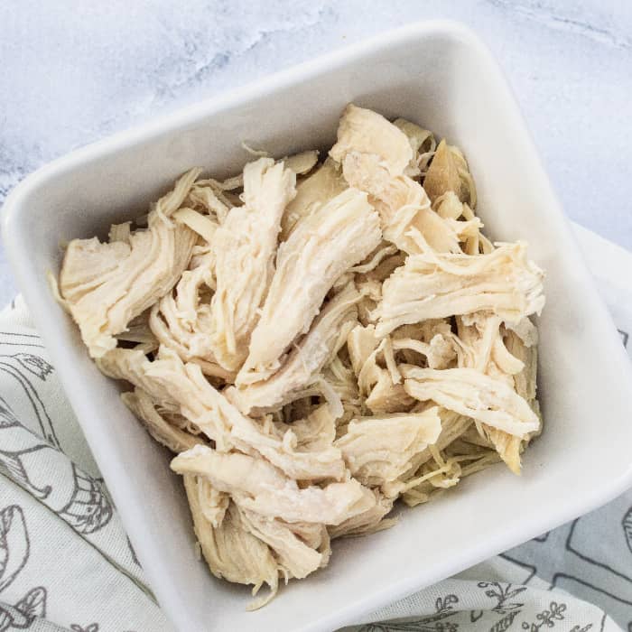 white bowl of shredded chicken cooked in the Instant Pot