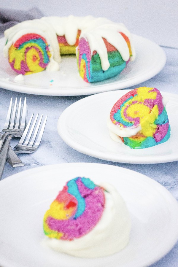 Slices of colorful Instant Pot rainbow bundt cake on white plates