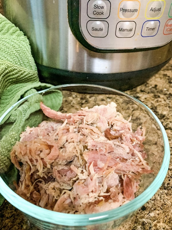 glass dish of pulled pork to be reheated in the Instant Pot