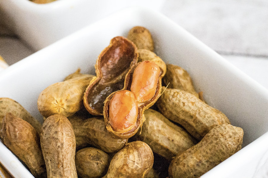 Cajun boiled peanuts with a shell open, displaying the tender peanuts inside