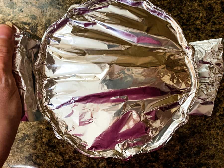 bundt pan covered with foil and resting on a foil sling to be lowered into an Instant Pot