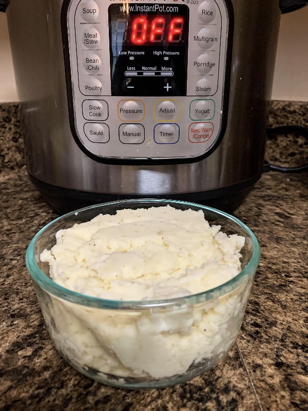 Glass bowl of mashed potatoes in front of an Instant Pot pressure cooker