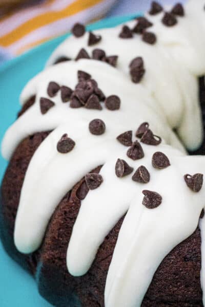 chocolate bundt cake with cream cheese frosting and chocolate chips on a turquoise plate
