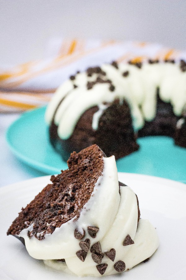 slice of Instant Pot chocolate chip bundt cake on a white plate in front of the whole cake on a turquoise plate