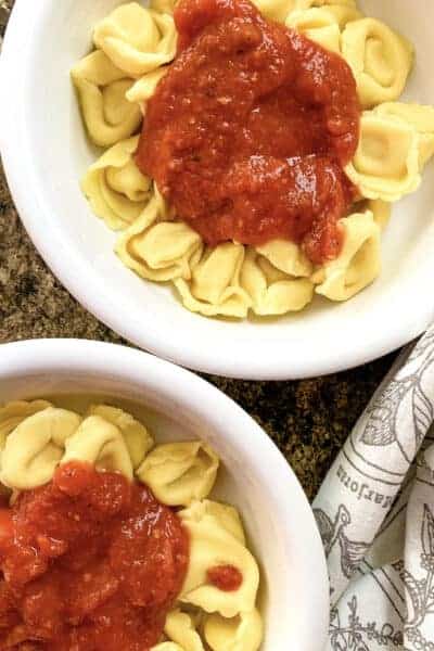 two bowls filled with tortellini cooked in the Instant Pot pressure cooker and topped with marinara sauce