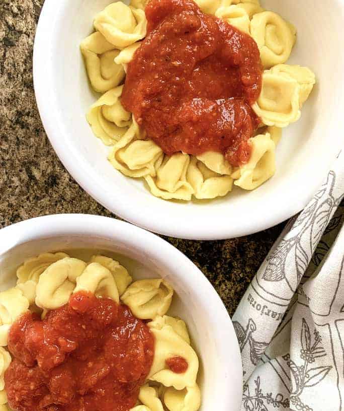 two bowls filled with tortellini cooked in the Instant Pot pressure cooker and topped with marinara sauce