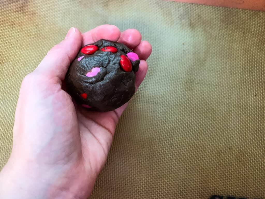 hand holding a ball of cookie dough made with brownie mix