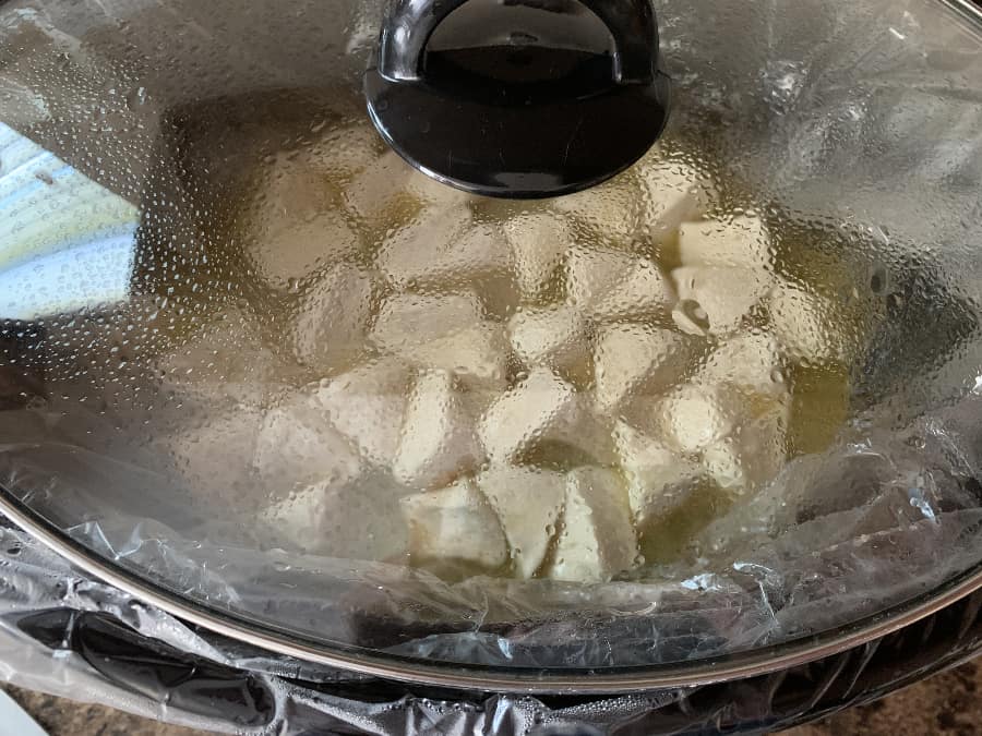crockpot with chicken and biscuit dumplings cooking inside