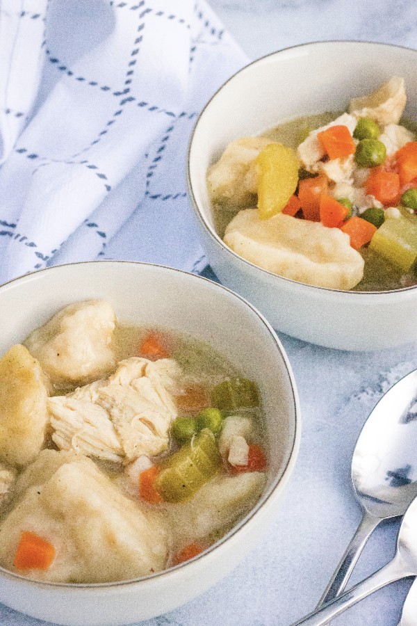 two white bowls filled with chicken and dumplings