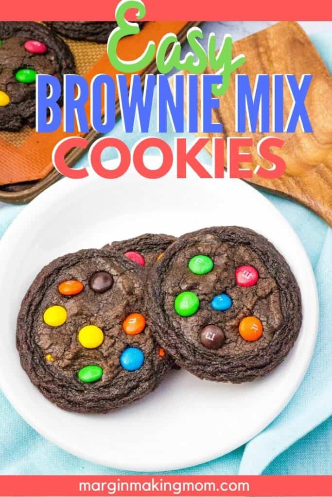 white plate of brownie mix cookies next to a baking sheet and wooden spatula