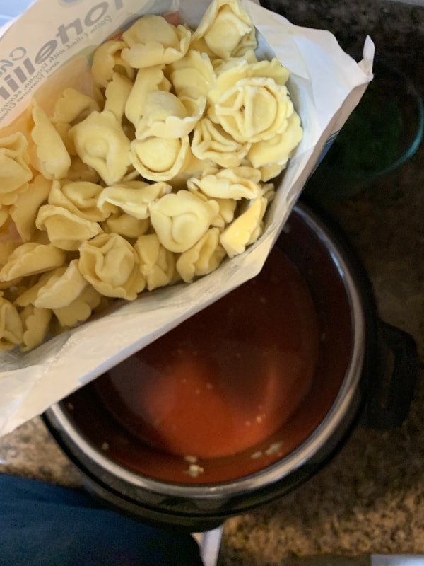 frozen cheese tortellini being added to the Instant Pot 