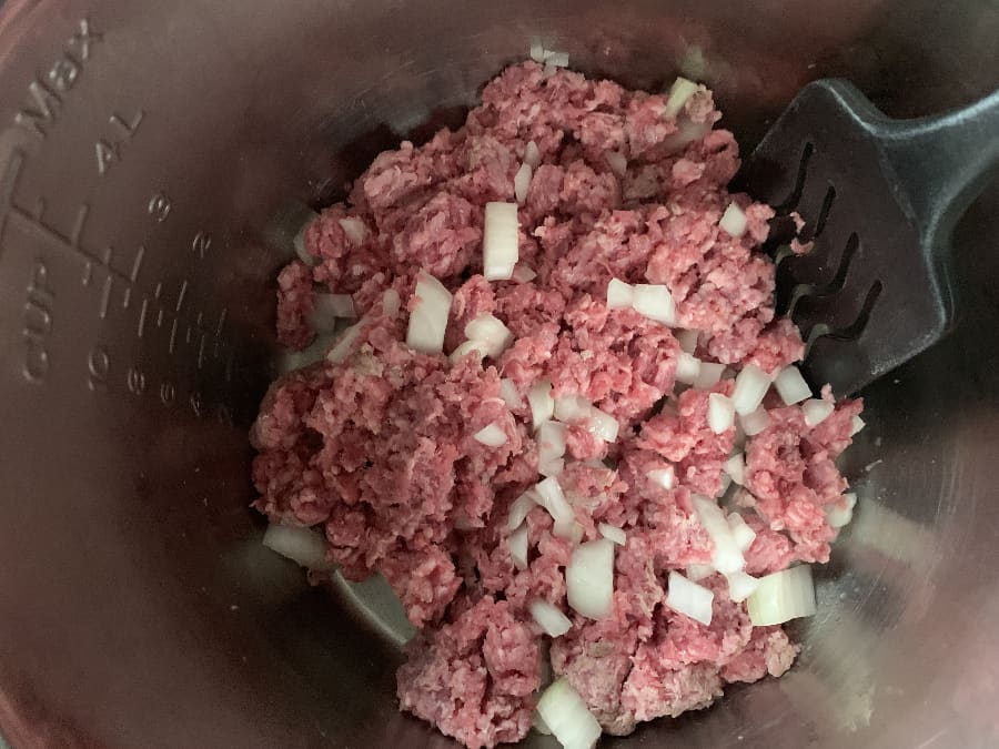 ground beef and onions in the insert pot of the Instant Pot