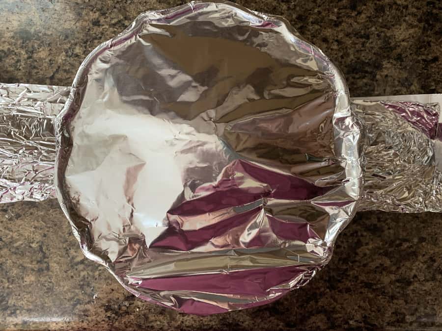 bundt pan covered with foil and resting on a foil sling