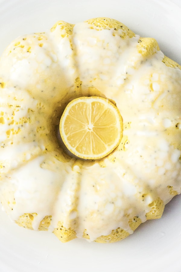 lemon poppy seed bundt cake on a white plate, with half a lemon in the middle