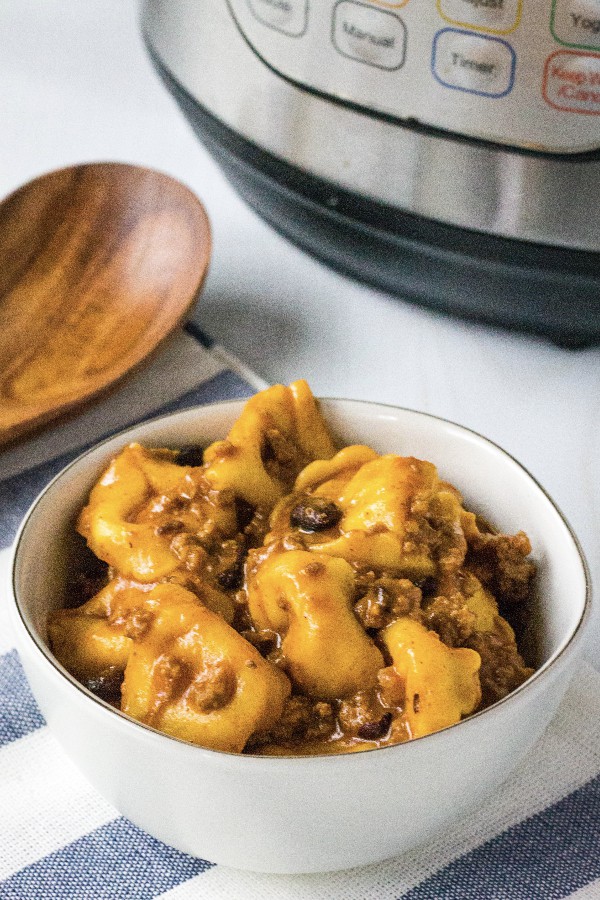 white bowl of enchilada tortellini casserole in front of an Instant Pot pressure cooker