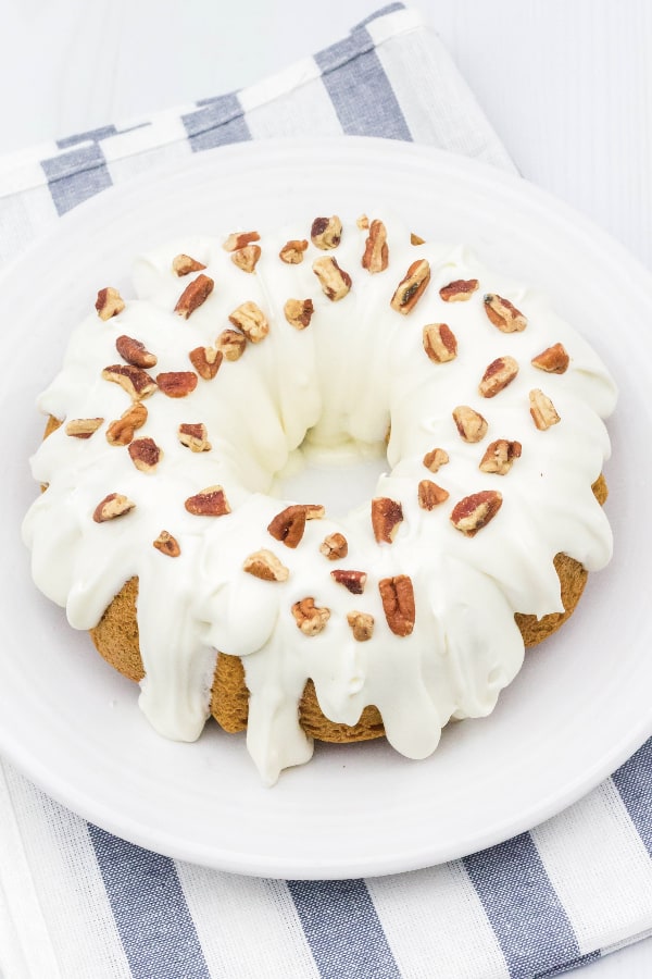 Instant Pot carrot bundt cake topped with cream cheese frosting on a white plate