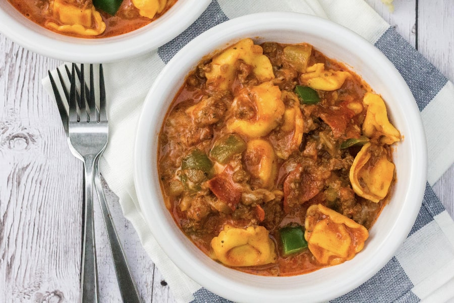 Easy Instant Pot pepperoni pizza tortellini in a white bowl, with forks next to the bowl