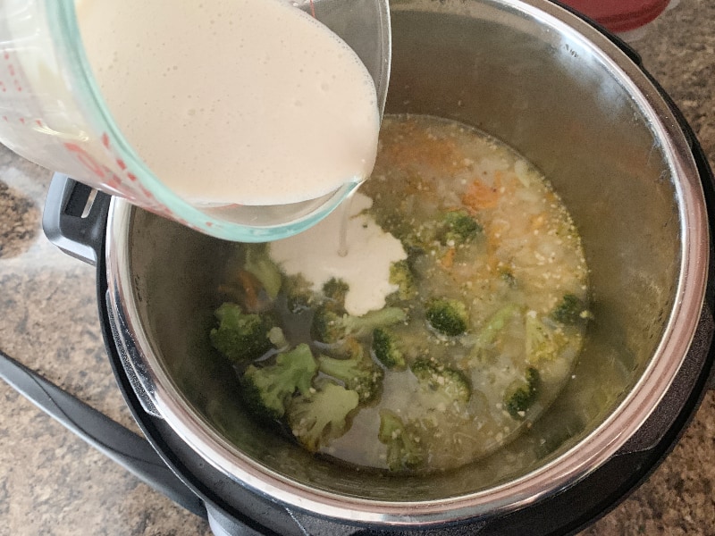 pouring slurry of flour and evaporated milk into broccoli soup