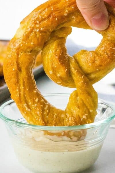 soft baked homemade pretzel being dipped in cheese