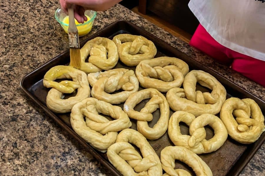 soft pretzels being brushed with an egg wash before baking