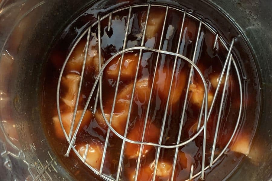 chicken and teriyaki sauce in an insert pot of the Instant Pot, with trivet on the chicken