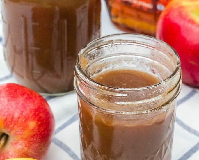 two jars of apple butter sweetened with maple syrup, next to some apples