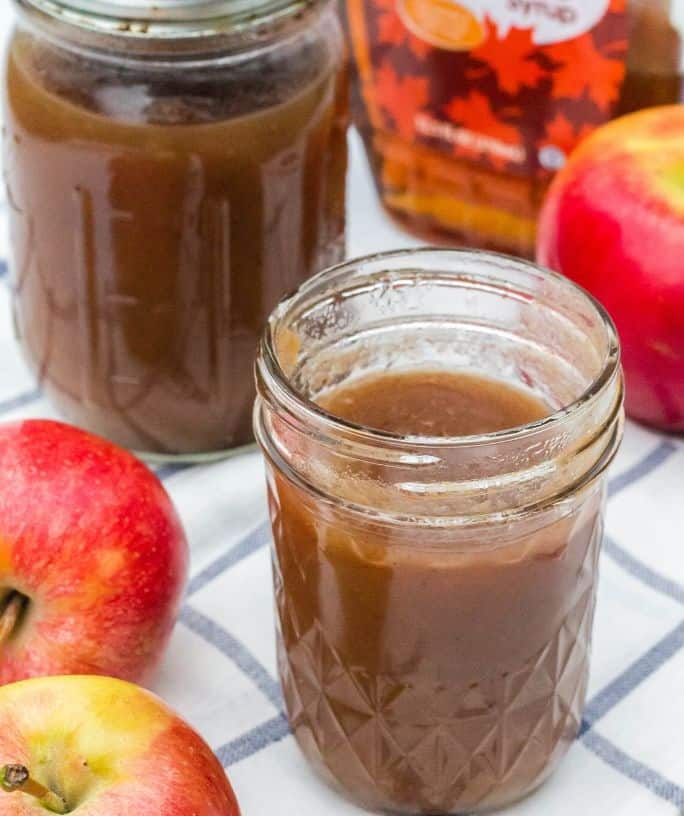 two jars of apple butter sweetened with maple syrup, next to some apples