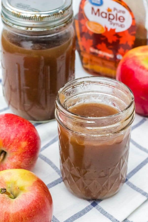 jar of Instant Pot apple butter made with maple syrup, next to some apples