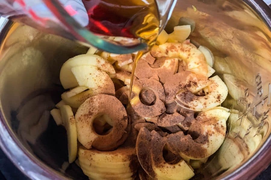 apples, spices, and maple syrup being combined in the Instant Pot to make apple butter
