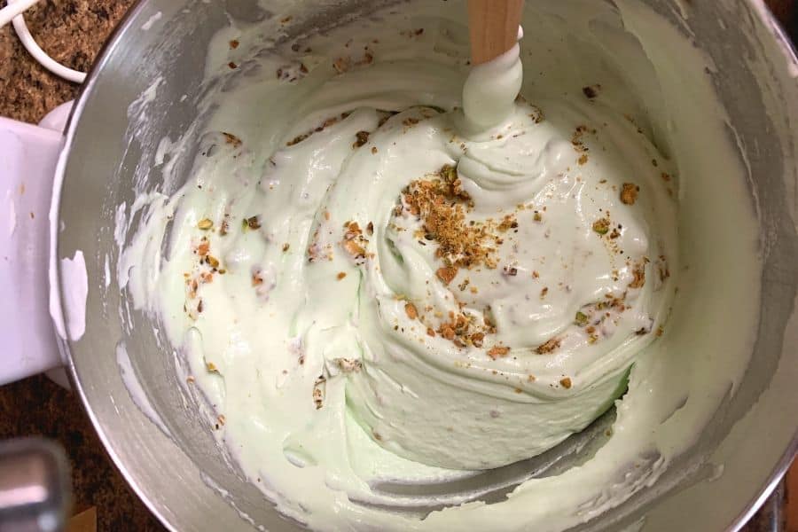 Creamy pistachio ice cream base being gently stirred before freezing