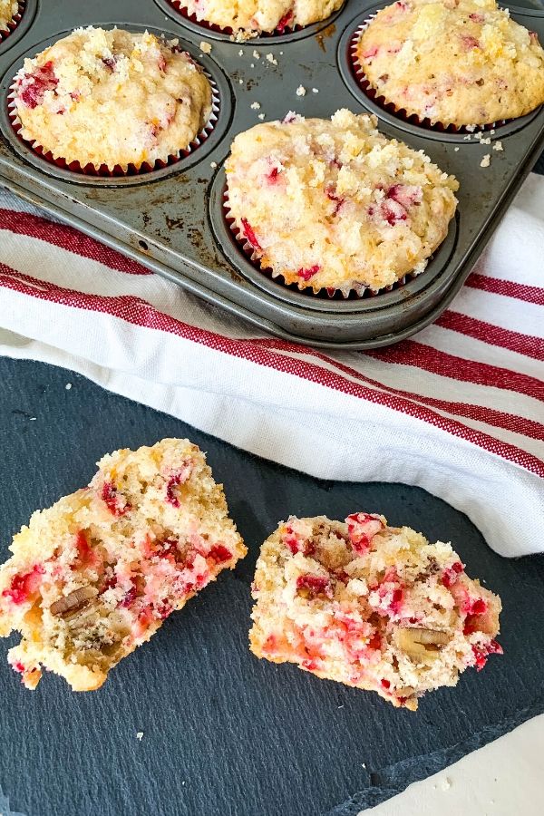 easy cranberry orange muffins with pecans and streusel on a black slate board next to a muffin tin