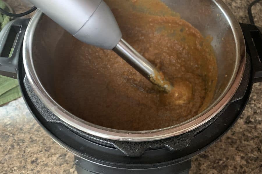 an immersion blender pureeing the pumpkin apple butter in the insert pot of the Instant Pot