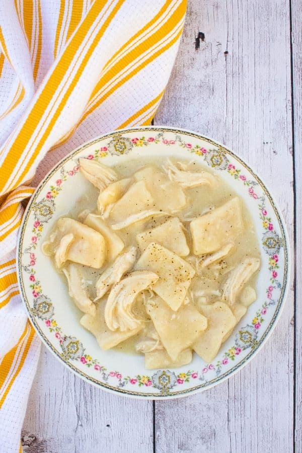 a china bowl with a floral pattern filled with a serving of chicken and flat dumplings