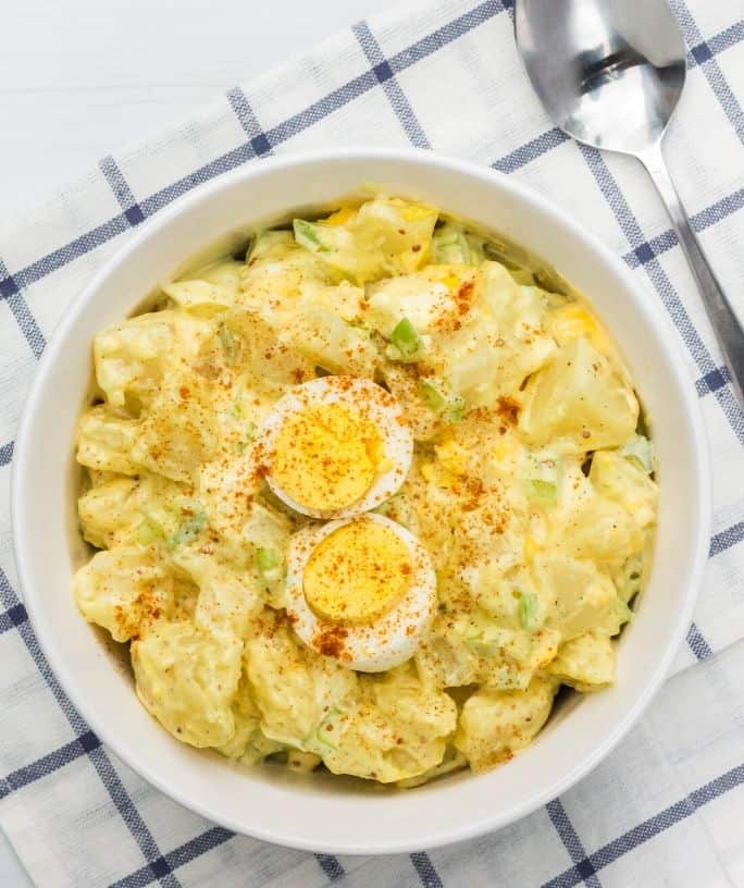 white serving dish of Instant Pot potato salad on a blue and white checkered towel