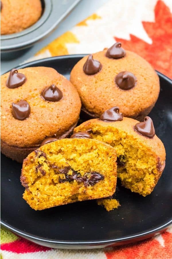 plate of pumpkin chocolate chip muffins, with one muffin cut in half