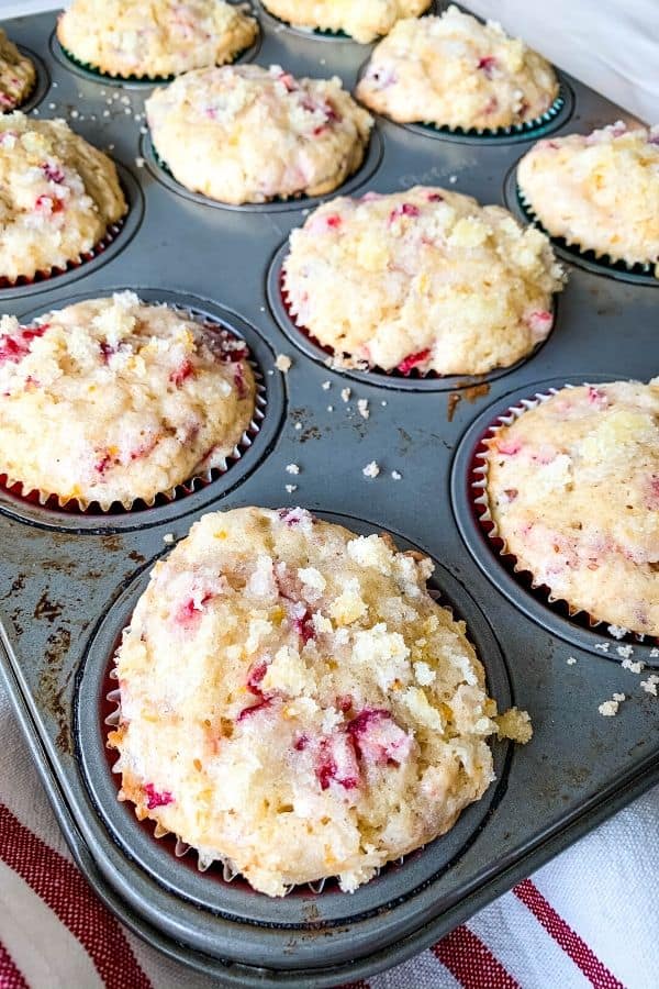 muffin tin filled with freshly baked cranberry orange muffins