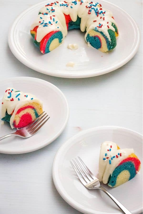 two slices of patriotic bundt cake on white plates, with the remainder of the cake on a serving plate in the background