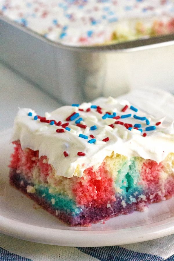 piece of patriotic poke cake in front of the pan that it baked in
