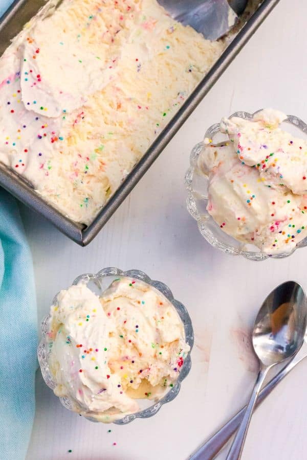 two dessert cups filled with cake batter ice cream, next to a pan of remaining ice cream.