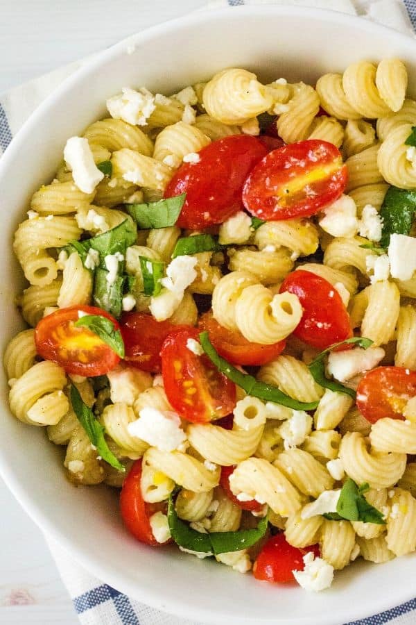 a bowl of pasta, tomatoes, and basil tossed with feta and homemade lemon vinaigrette dressing