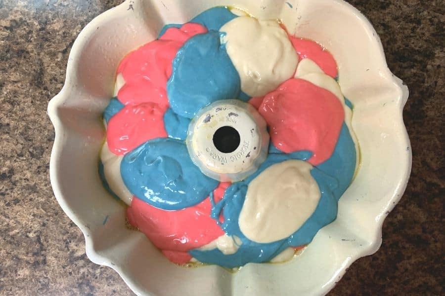red, white, and blue cake batters layered in a bundt pan