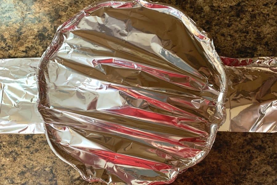 bundt pan covered with foil, sitting on a foil sling to be lowered into the Instant Pot