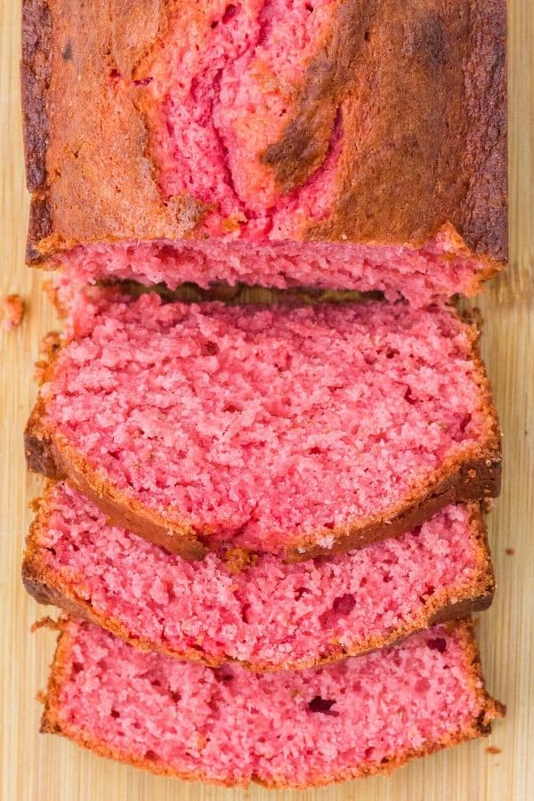 overhead view of a sliced loaf of strawberry banana bread on a cutting board