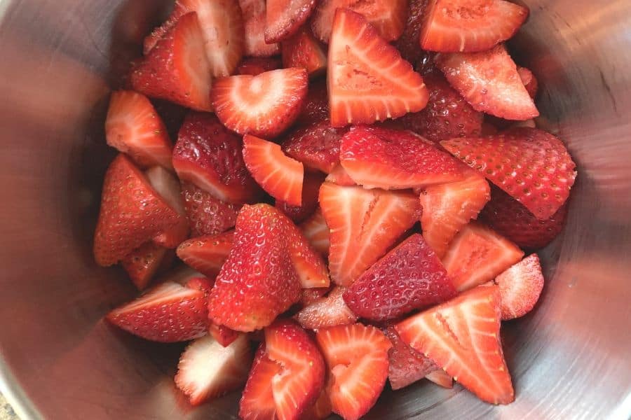 a bowl of quartered and stemmed strawberries