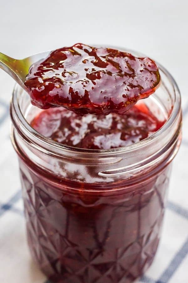 spoon scooping Instant Pot strawberry jam out of a glass jar