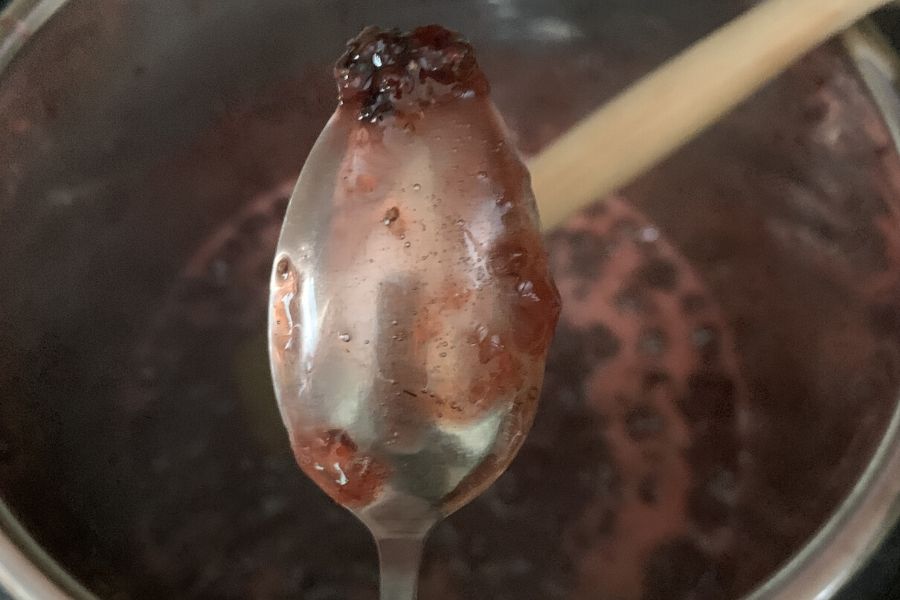 metal spoon with gelled strawberry jam on it, demonstrating the spoon test for jam