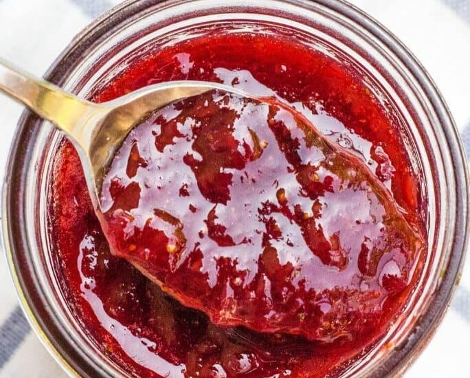 spoon scooping out some strawberry jam from a jar