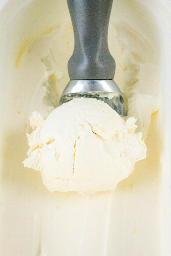an ice cream scoop scooping out some of the homemade lemon ice cream