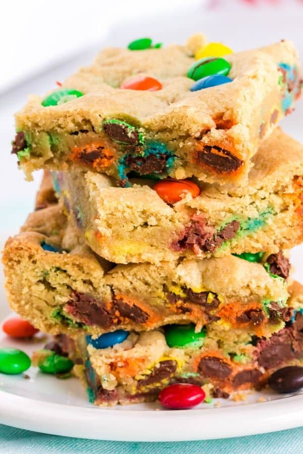 a stack of M&M cookie bars on a white plate