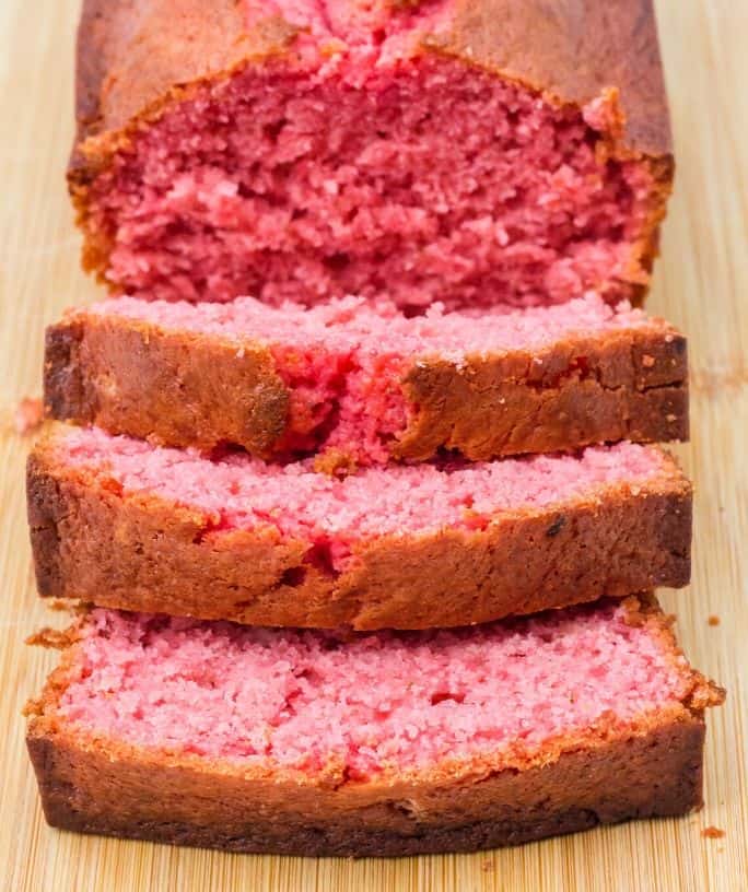 sliced loaf of strawberry banana bread on a cuttinb board